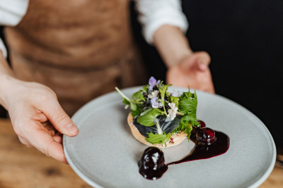 A server holding a plate with a beautifully presented dish