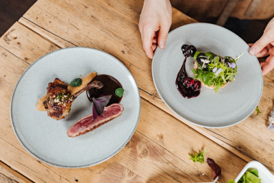 Zwei angerichtete Teller. Zwei Hände greifen nach einem