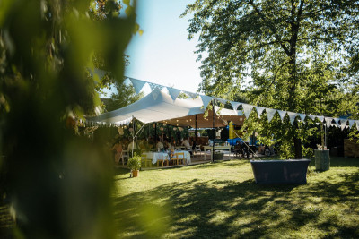 Sommerfest im Grünen, ein Zelt und darunter gedeckte Tische